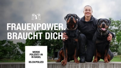 Person in Uniform mit zwei Hunden im Freien.