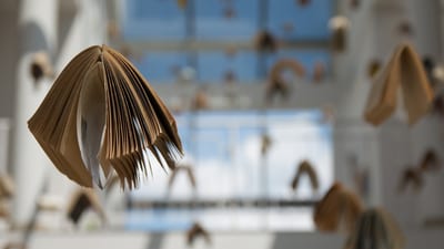 Schwebende Bücher vor Glasdecke in modernem Gebäude.