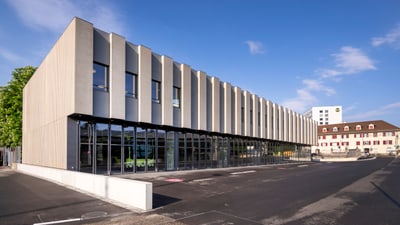 Modernes Gebäude mit Fenstern und Parkplatz bei Tageslicht.