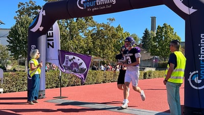 Ein American-Football-Spieler läuft durch einen Ziellinie-Bogen.