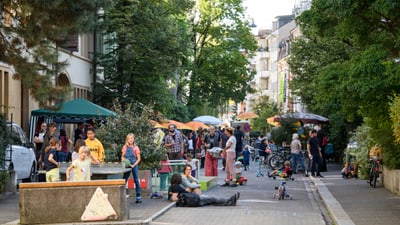 Menschen geniessen Tag in belebter Wohnstrasse.