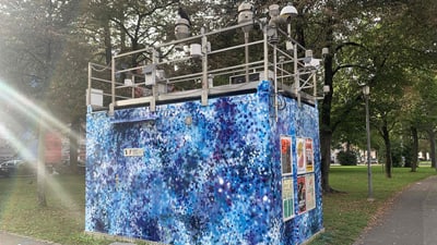 Ein gemaltes Gebäude mit blauer Wand und Kameraausrüstung auf dem Dach im Park.