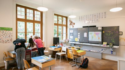 Kinder, die in einem Klassenzimmer nach draussen schauen.