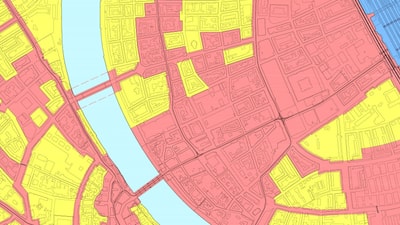 Stadtplan mit verschiedenen farbigen Zonen gelb, rot und blau und einem Fluss in der Mitte.