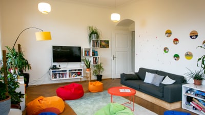 Gemütliches Wohnzimmer mit bunten Sitzsäcken und grauem Sofa.