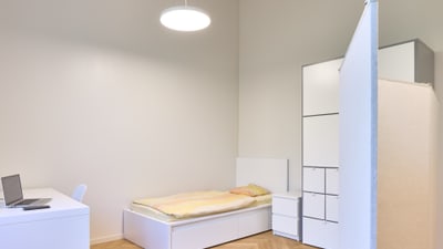 Ein Schlafzimmer mit Einzelbett, Schreibtisch und Schrank.