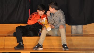 Zwei Jungen sitzen auf Tribüne und essen Popcorn.",