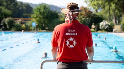 Rettungsschwimmer in rotem Hemd beobachtet das Schwimmbecken.