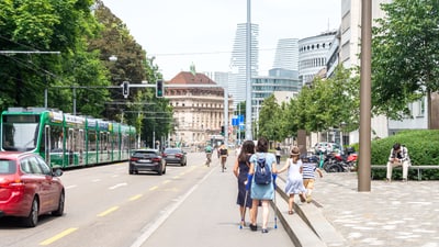 Fussgänger, Autos und Strassenbahn in städtischer Umgebung.