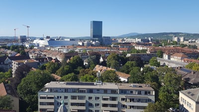 Panoramaansicht von Basel mit Hochhäusern und grünen Bäumen.