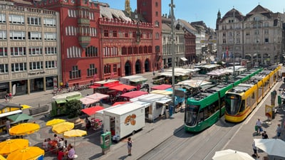 Marktplatz mit bunten Strassenbahnen und historischem Rathausim Hintergrund.