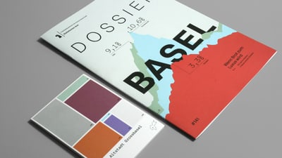 Broschüre und Karte mit Basel-Design auf grauem Hintergrund.