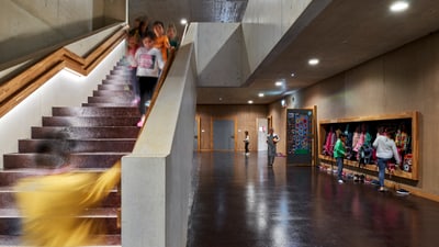 Treppenhaus mit Kindern auf der Treppe und neben der Treppen eine Garderobe.