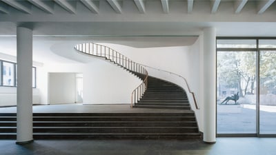 Modernes Treppenhaus mit gebogener Treppe in einem minimalistischen Gebäude.