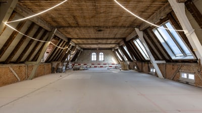 Leerer Dachboden mit Holzboden und schrägen Fenstern.