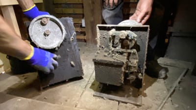 Zwei verrostete Maschinen, von Hand gehalten, in dunklem Raum.