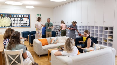 Menschen in einem Gemeinschaftsraum mit Sofas und Wanddekoration.