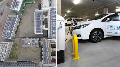 Luftaufnahme von Gebäuden mit Solarpanels und E-Auto an Ladestation.