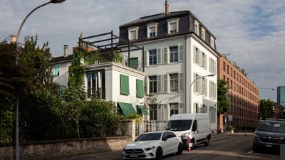 Wohngebäude mit Autos auf der Strasse, bepflanzter Balkon.