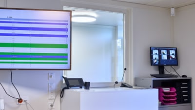 Büro mit Monitoren und Schreibtisch mit Geräten.",