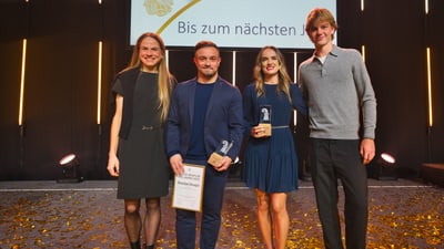 Vier Personen auf einer Bühne mit Auszeichnungen.