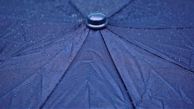 Nahaufnahme eines regennassen blauen Regenschirms.
