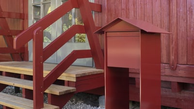 Rotes Gebäude mit Briefkasten und Holzbalkontreppe.