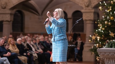 Frau hält Rede in festlicher Umgebung.