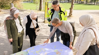 Fünf Personen betrachten eine Karte im Freien.