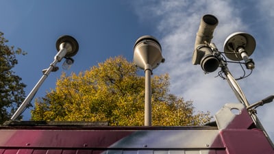 Strassenlaternen und Überwachungskameras vor Herbstbaum.