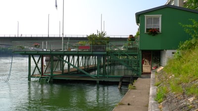 Grünes Garderobenhäuschen am Rheinufer und der zweistöckige Steg, der auf den Rhein führt.