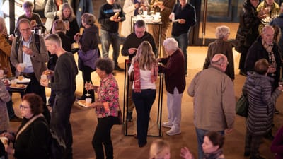 Menschenmenge bei einer Veranstaltung, viele essen und trinken.