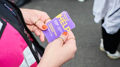 Person hält eine lila Karte in der Hand auf der Strasse.