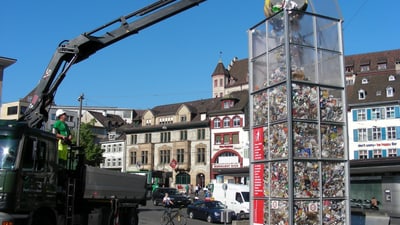 Lastwagen entleert grossen Mülleimer in Basel Stadtplatz.