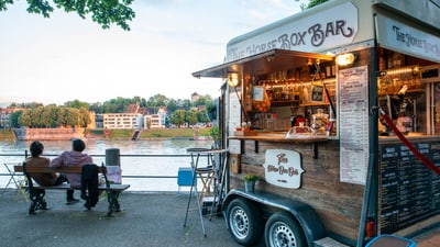 Lebensmittelwagen am Flussufer bei Sonnenuntergang.