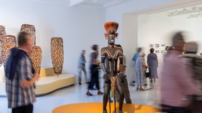 Ausstellung mit Skulptur und bewegten Menschen.