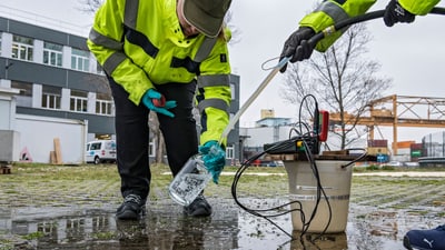 Zwei Arbeiter in Warnwesten sammeln Wasserproben.