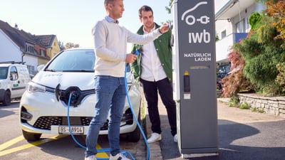 Zwei Männer laden ein Elektroauto an einer Ladestation auf.