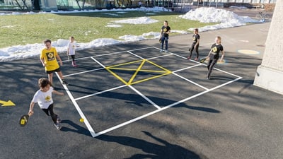 Personen spielen auf einem markierten Feld im Freien.