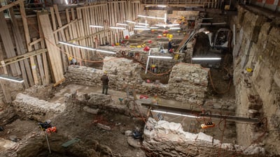 Archäologische Ausgrabungsstätte mit Holzstützen und Beleuchtung.