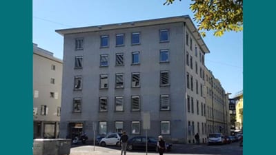 Mehrstöckiges Gebäude an Strassenecke bei Tag.