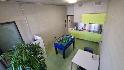 Kleiner Raum mit Tischfussballspiel, Tisch und Pflanzen.