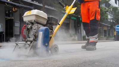 Arbeiter mit Maschine zur Strassenbearbeitung.