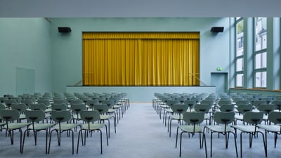 Leerer Konferenzraum mit gelbem Vorhang auf der Bühne.