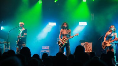 Live-Band-Performance auf beleuchteter Bühne mit grünem Licht.