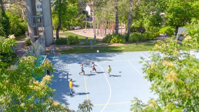 Kinder spielen Basketball auf einem Aussenplatz im Park.