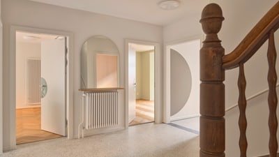 Moderne Eingangshalle mit Holztreppe und Türen zu mehreren Räumen.