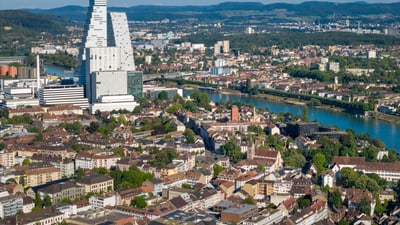 Luftaufnahme der Stadt mit Fluss, Bergen und modernem Hochhaus.