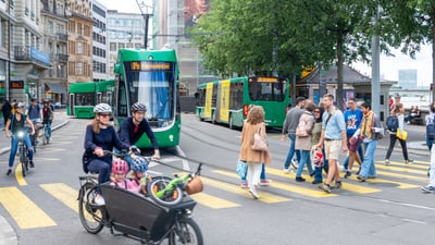 Verkehr und Fussgänger auf belebter Strasse mit Strassenbahn.