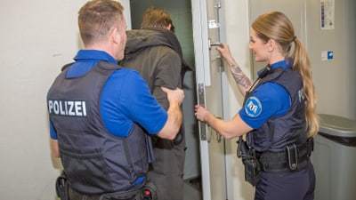 Zwei Sicherheitsassistenten nehmen einen Gefangenen in Gewahrsam